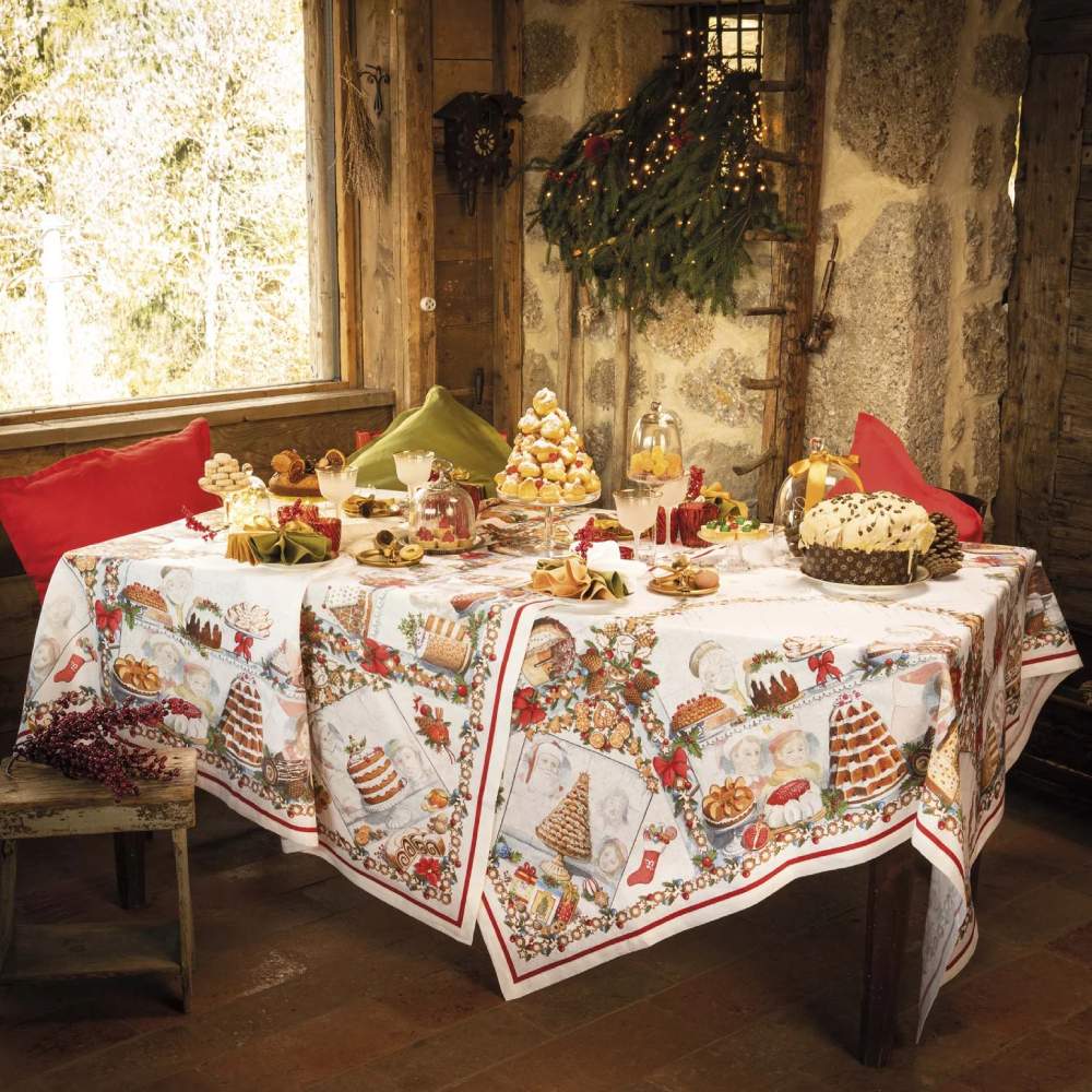 Tovaglia natalizia Noel Gourmand in puro lino di Tessitura Toscana Telerie. Fantasia su fondo chiaro, con scene che ritraggono dolci natalizi e tavole imbandite nel periodo di Natale. Le scene ritratte sono ricche di dettagli e fanno respirare aria di festa. La fantasia è incorniciata da una riga rossa e da una ghirlanda di biscotti a tema natalizio. Misura rettangolare x12 (170x270 cm).