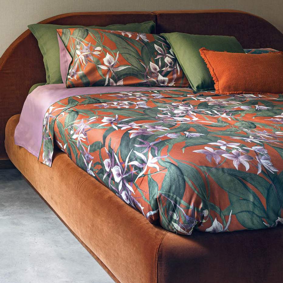 Trapunta Invernale matrimoniale Fazzini Amazzonia, in raso di puro cotone. Le orchidee e la foresta amazzonica colorano le lenzuola e trapunta proposte nei toni vibranti del malva accostato al ruggine. Il lato superiore delle federe e la balza del lenzuolo di sopra sono in raso di cotone stampato in digitale. Il resto del completo è in percalle di cotone tinta unita malva