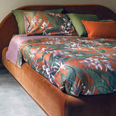 Trapunta Invernale matrimoniale Fazzini Amazzonia, in raso di puro cotone. Le orchidee e la foresta amazzonica colorano le lenzuola e trapunta proposte nei toni vibranti del malva accostato al ruggine. Il lato superiore delle federe e la balza del lenzuolo di sopra sono in raso di cotone stampato in digitale. Il resto del completo è in percalle di cotone tinta unita malva