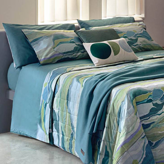 Completo lenzuola Fazzini Atolli, in percalle di puro cotone. Misura francese. Il completo lenzuola Atolli presenta una fantasia che richiama il movimento delle onde del mare. I colori sono quelli che si potrebbero ammirare mentre ci si rilassa in spiaggia, quindi varie tonalità di azzurro, verde acqua, ottanio. Il lato superiore delle federe e la balza del lenzuolo di sopra sono in percalle di cotone stampato in digitale. Il resto del completo è in percalle di cotone tinta unita color petrolio.