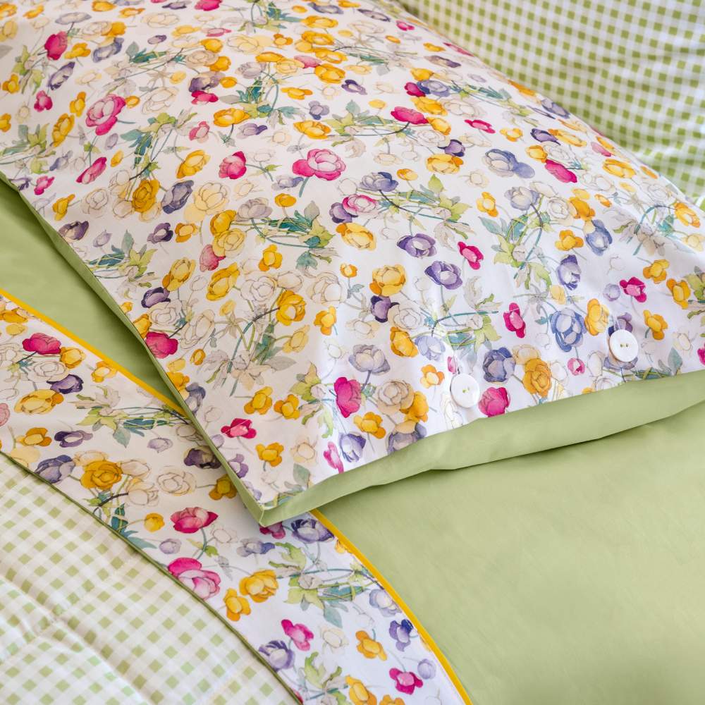 Completo lenzuola matrimoniale Fazzini Blooms, in percalle di puro cotone. Fantasia vivace e colorata, con fiori di campo stampati su lenzuolo di sopra e federe . Le federe con bottoni in madreperla e la balza del lenzuolo di sopra, impreziosito da codina a contrasto, sono in percalle di cotone stampato in digitale. Il resto del completo è in percalle tinta unita verde.