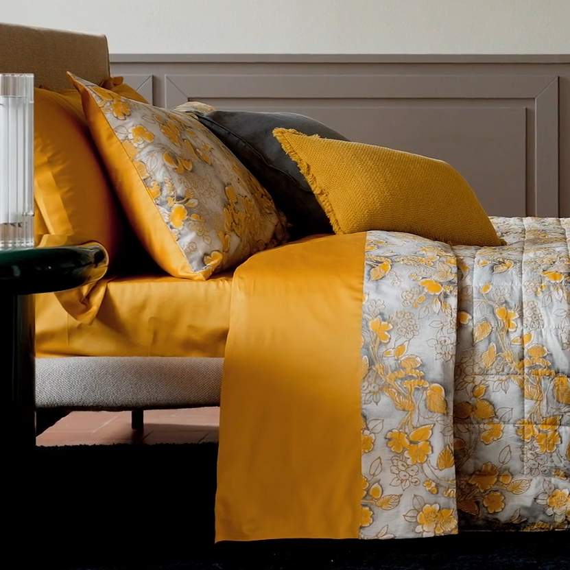 Completo lenzuola matrimoniale Fazzini Chinoiserie, in raso di puro cotone. La passione per le ceramiche orientali anima la collezione Chinoiserie. Il disegno floreale emerge sul fondo dall'effetto acquerellato e diventa tridimensionale grazie al profilo floccato e dorato. Il lato superiore delle federe e la balza del lenzuolo di sopra sono in raso di puro cotone tinto e sovrastampato con effetto tridimensionali laminati. Il resto del completo è in raso di cotone tinta unita oro ocra.
