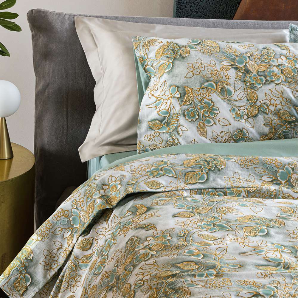 Completo lenzuola matrimoniale Fazzini Chinoiserie, in raso di puro cotone. La passione per le ceramiche orientali anima la collezione Chinoiserie. Il disegno floreale emerge sul fondo dall'effetto acquerellato e diventa tridimensionale grazie al profilo floccato e dorato. Il lato superiore delle federe e la balza del lenzuolo di sopra sono in raso di puro cotone tinto e sovrastampato con effetto tridimensionali laminati. Il resto del completo è in raso di cotone tinta unita verde acqua.