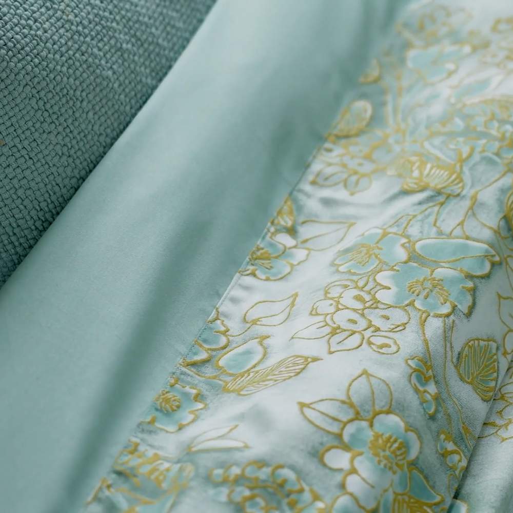 Completo lenzuola matrimoniale Fazzini Chinoiserie, in raso di puro cotone. La passione per le ceramiche orientali anima la collezione Chinoiserie. Il disegno floreale emerge sul fondo dall'effetto acquerellato e diventa tridimensionale grazie al profilo floccato e dorato. Il lato superiore delle federe e la balza del lenzuolo di sopra sono in raso di puro cotone tinto e sovrastampato con effetto tridimensionali laminati. Il resto del completo è in raso di cotone tinta unita verde acqua.