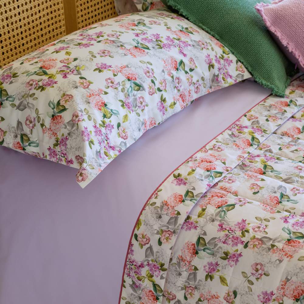 Completo lenzuola matrimoniale Fazzini Corolle, in percalle di puro cotone. La fantasia Corolle, romantica e sensoriale, porta in camera da letto il profumo inebriante delle più belle fioriture nelle varie sfumature del rosa. Le federe a 4 volanini e la balza del lenzuolo di sopra sono in percalle di cotone stampato in digitale. Il resto del completo è in percalle di cotone colore lilla/glicine
