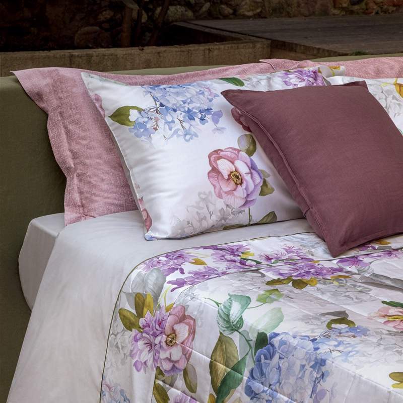 Completo lenzuola matrimoniale Fazzini Camelia, in percalle di puro cotone. La fantasia floreale del lenzuolo Camelia rende omaggio al fascino dei giardini italiani. Le camelie, le ortensie e le fresie fioriscono sulla balza del lenzuolo facendo incontrare in una delicata armonia il malva, l’azzurro e il bianco. La faccia superiore delle federe e la balza del lenzuolo di sopra sono in percalle di cotone stampato. Il resto del completo è in tinta unita.