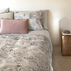 Completo lenzuola matrimoniale Fazzini Giardini d'Oriente, in pregiato percalle e raso di puro cotone. La collezione Giardini d'Oriente presenta una romantica fantasia floreale che ricorda i tessuti pregiati di fine Ottocento. Sul raso di cotone prendono vita rami in fiore e affascinanti uccelli dalle meravigliose piume. Colore grigio. La fantasia è presente sulla faccia superiore delle federe e sulla balza del lenzuolo di sopra, in raso di cotone. Il resto del completo è in percalle di cotone tinta unita.