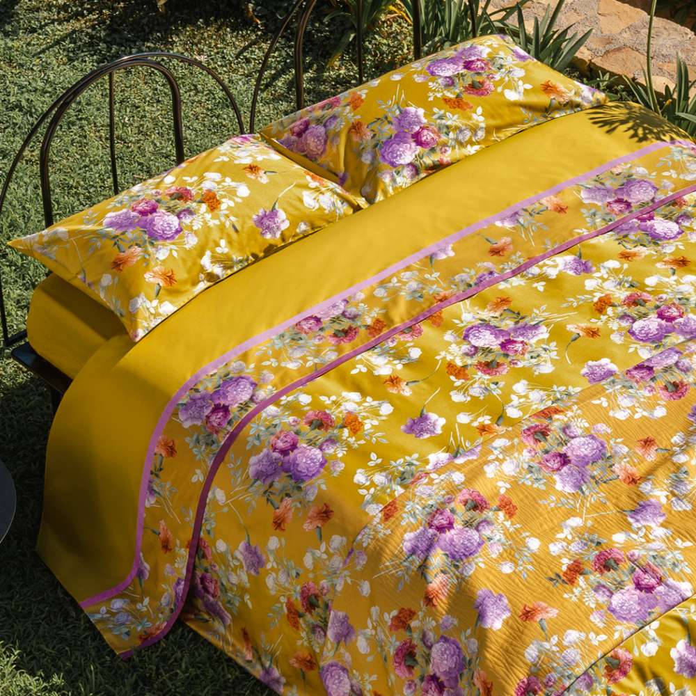 Completo lenzuola matrimoniale Fazzini Summer, in percalle e raso di puro cotone. La fantasia Summer è ispirata dalla bellezza del garofano. Il disegno romantico e vivido dei fiori decora le federe e la balza superiore del lenzuolo di sopra, entrambe in raso di cotone. Colore giallo ocra. La fantasia è presente sulla faccia superiore delle federe e sulla balza del lenzuolo di sopra, entrambe in raso di cotone. Il resto del completo è in percalle tinta unita ocra.