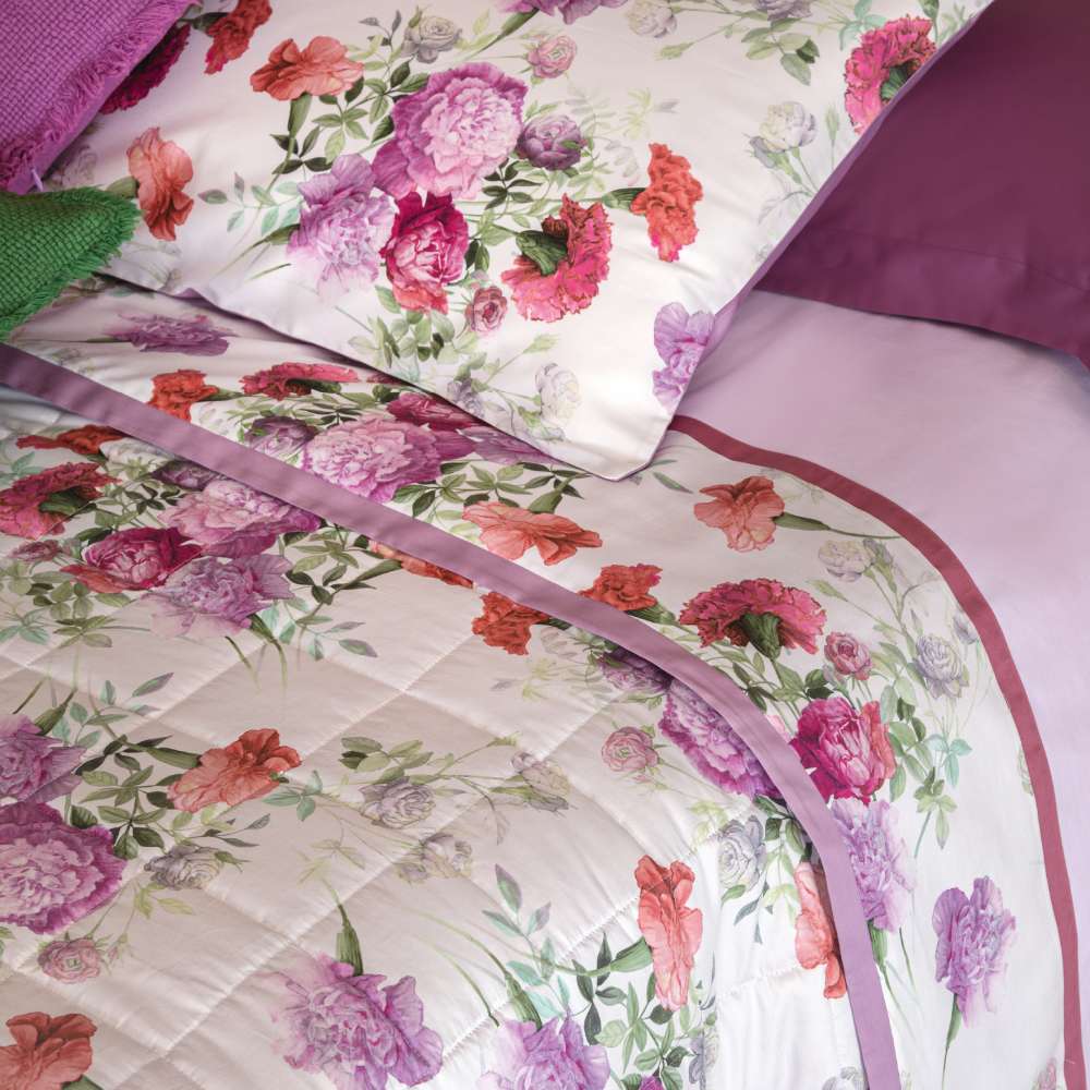 Completo lenzuola matrimoniale Fazzini Summer, in percalle e raso di puro cotone. La fantasia Summer è ispirata dalla bellezza del garofano. Il disegno romantico e vivido dei fiori decora le federe e la balza superiore del lenzuolo di sopra, entrambe in raso di cotone. Colore rosa glicine. La fantasia è presente sulla faccia superiore delle federe e sulla balza del lenzuolo di sopra, entrambe in raso di cotone. Il resto del completo è in percalle tinta unita rosa.