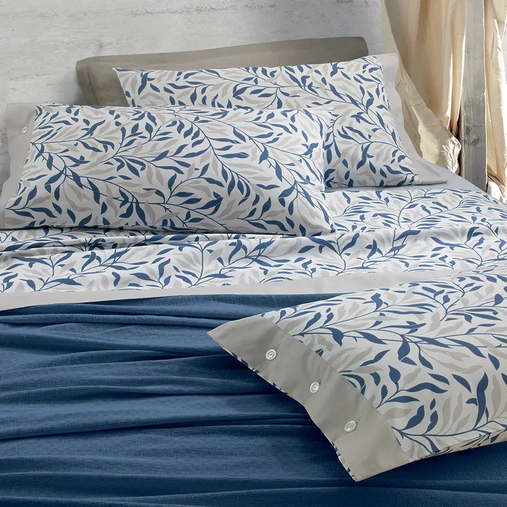 Completo lenzuola matrimoniale Gabel Olimpia in cotone. Lenzuolo superiore e federe in fantasia con foglie beige e blu. Lenzuolo sotto con angoli bianco con righe beige.