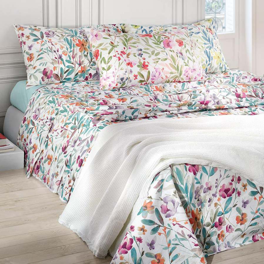 Lenzuolo Copriletto matrimoniale Amelie, in percalle di cotone. Realizzato in Italia da Somma. Il completo lenzuola Amelie è caratterizzato da una vivace fantasia floreale in tre varianti di colore: la prima con fiori arancione e foglie verde salvia, la seconda con fiori rosso/corallo e malva e foglie verdi, la terza con fiori gialli e foglie bluette. La stampa è presente sulle federe e sul lenzuolo superiore, compresa la balza. Il lenzuolo con angoli è in falso unito color verde acqua, rosa o giallo.