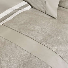 Completo lenzuola matrimoniale Fazzini Sashiko, in pregiato raso di puro cotone. Il completo lenzuola Sashiko presenta una moderna fantasia a puntini, con una doppia sovrastampa che dona tridimensionalità e movimento alla microfantasia. Variante di colore grigio. Le federe e il lenzuolo di sopra, impreziositi da balza tinta unita e codina inserita, sono in raso di puro cotone fantasia. Il resto del completo è in raso di puro cotone tinta unita.