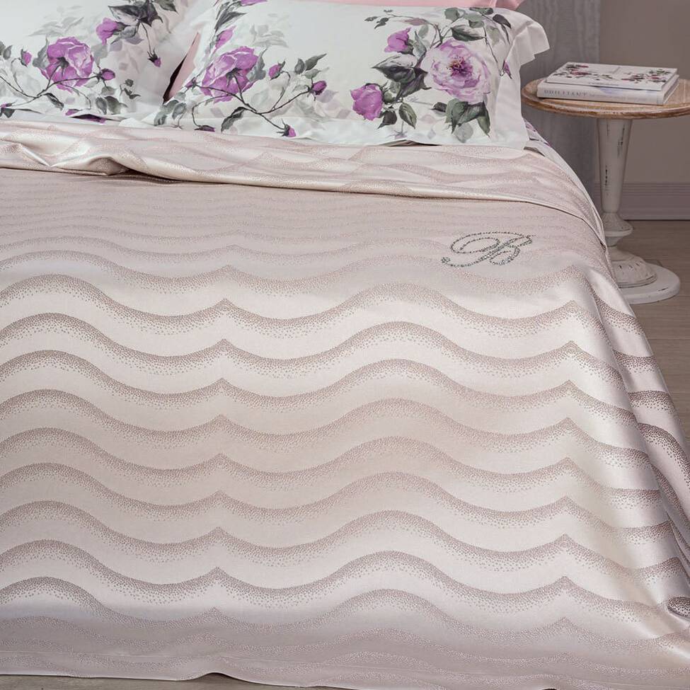 Copriletto Estivo matrimoniale Jasmine di Blumarine, in elegante raso jacquard. La coperta estiva Jasmine è caratterizzata da un sensuale motivo jacquard a onde ed è arricchita dal logo Blumarine in preziosi cristalli Swarovski. Disponibile nella variante di colore rosa cipria