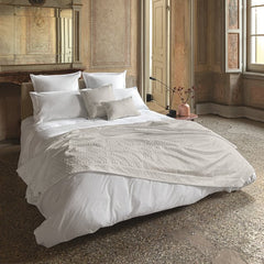 Copriletto matrimoniale Villa Necchi, della linea Fazzini Atelier, in prezioso raso jacquard. La coperta estiva Villa Necchi presenta in un gioco tono su tono un bel motivo tridimensionale d'ispirazione dèco, con una mano morbida e voluminosa. Variante di colore champagne/avorio. Il copriletto Villa Necchi è trapuntato a capo e rifinito a mano con due angoli sagomati che lo adattano perfettamente agli angoli del letto.