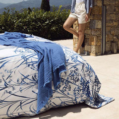 Copripiumino matrimoniale Fazzini Fields, in percalle di puro cotone. La fantasia del completo lenzuola Fields ritrae lunghi steli su cui sbocciano fiori campestri che sembrano appena mossi dalla brezza. Il bianco del fondo appare luminoso, per poi svanire pian piano nel disegno che si fa sempre più fitto. Colore blu.