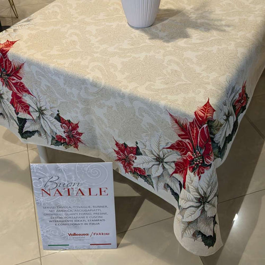 Copritavolo Natalizio Favola di Emily Home, in tessuto Gobelin. Misura rettangolare x12 (140x260 cm) Il copritavolo Favola presenta una delicata fantasia floreale natalizia su fondo platino. Sugli angoli risaltano stelle di Natale bianche e rosse