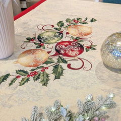 Copritavolo Natalizio Sweet Red Christmas di Emily Home, in tessuto Gobelin. Misura rettangolare x12 (140x260 cm) Il copritavolo Red Christmas è caratterizzato da una cornice rossa con impresso un motivo a ricamo color crema, con decorazioni natalizie sugli angoli. Il piano tavola presenta invece un fondo chiaro con motivo damascato, su cui da cornice a tutta la tovaglia. Al centro è presente una decorazione con rami di agrifoglio e sfere rosse e dorate.