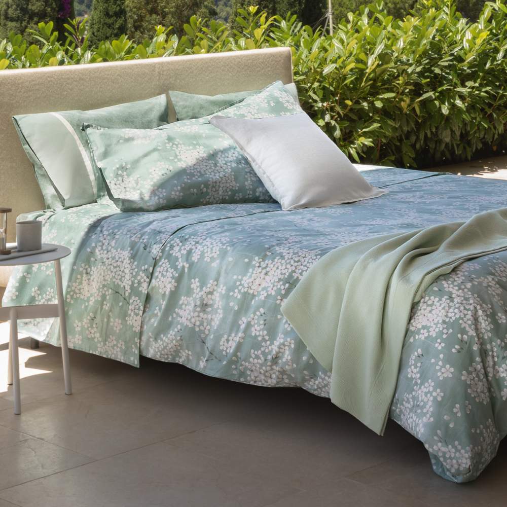 Lenzuolo Copriletto matrimoniale Fazzini Kimono in percalle di puro cotone. Il lenzuolo di sopra e le federe con quattro volanini sono in percalle di puro cotone stampato. Anche il risvolto del lenzuolo è stampato. Fantasia floreale con fiorellini bianchi su fondo verde acqua