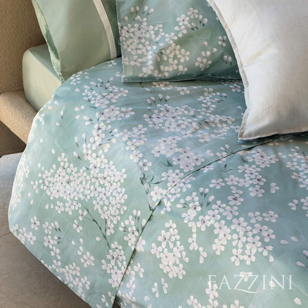 Lenzuolo Copriletto matrimoniale Fazzini Kimono in percalle di puro cotone. Il lenzuolo di sopra e le federe con quattro volanini sono in percalle di puro cotone stampato. Anche il risvolto del lenzuolo è stampato. Fantasia floreale con fiorellini bianchi su fondo verde acqua