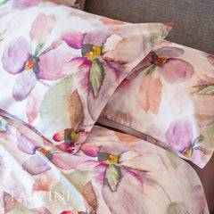 Lenzuolo copriletto matrimoniale Fazzini Trasparenze, in percalle di puro cotone. Il completo lenzuola Trasparenze ricrea, tramite la tecnica dell'acquerello, una luminosa fantasia floreale che esplora le varie tonalità del rosa. La fantasia è presente sulla faccia superiore delle federe a 4 volanini e sul lenzuolo di sopra. Anche la balza del lenzuolo di sopra è stampata, essendo un lenzuolo copriletto. Il resto del completo è il percalle di cotone tinta unita rosa.