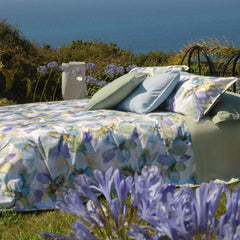 Lenzuolo copriletto matrimoniale Fazzini Trasparenze, in percalle di puro cotone. Il completo lenzuola Trasparenze ricrea, tramite la tecnica dell'acquerello, una luminosa fantasia floreale sui toni del verde e dell'azzurro. La fantasia è presente sulla faccia superiore delle federe a 4 volanini e sul lenzuolo di sopra. Anche la balza del lenzuolo di sopra è stampata, essendo un lenzuolo copriletto. Il resto del completo è il percalle di cotone tinta unita verde.