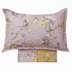 Lenzuolo copriletto matrimoniale Atelier 31, di Tessitura Randi, in percalle di puro cotone. Romantica fantasia con fiori chiari su fondo glicine. La fantasia con fondo glicine è presente sul lenzuolo di sopra e sulle federe. Il risvolto del lenzuolo di sopra è stampato, essendo un lenzuolo copriletto. Il lenzuolo con angoli presenta la stessa fantasia ma con fondo giallo ocra.