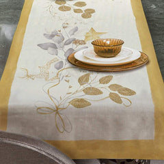 Corsia natalizia Mirage di Tessitura Randi. Stampata in digitale su tessuto di puro cotone. Il runner Mirage, con bordo ocra e fondo avorio, presenta una delicata fantasia con foglie, nastrini ed elementi tipici del Natale nei colori oro e grigio. Misura: 50x150 cm