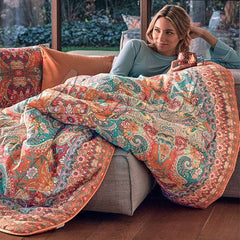 Scaldotto Alhambra di Caleffi, in cotone caldo con stampa digitale. Vivace fantasia multicolore, variante ambra. Lo Scaldotto è un morbido plaid con esterno in cotone smerigliato effetto cashmere, che offre una sensazione di morbidezza e comfort sulla pelle.