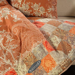 Scaldotto Caleffi Berry. Fantasia con piante e uccelli su fondo ambra/arancio e bordo patchwork. Plaid in cotone caldo.