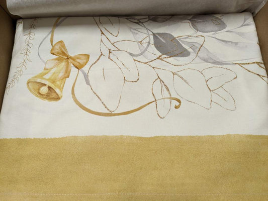 Tovaglia natalizia Mirage di Tessitura Randi. Stampa digitale su panama di puro cotone.  Fantasia su fondo avorio con delicata fantasia con foglie, nastrini ed elementi tipici del Natale nei colori oro e grigio.  Disponibile nella misura rettangolare x12 (150x270 cm) o x18 (150x360 cm). dettaglio fantasia bordo ocra