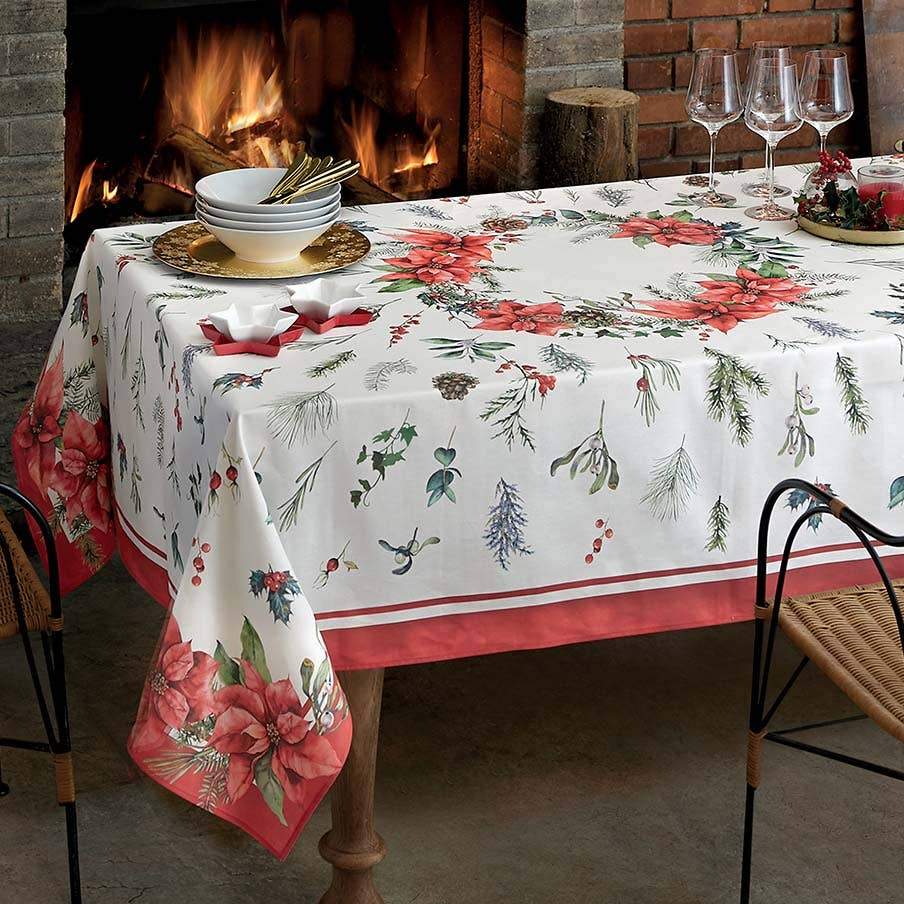 Tovaglia natalizia Chaplet di Gabel. Tovaglia in panama di puro cotone con fantasia piazzata. La tovaglia Chaplet presenta una raffinata fantasia natalizia, con una ghirlanda di stelle di Natale al centro e un elegante bordo di colore rosso.