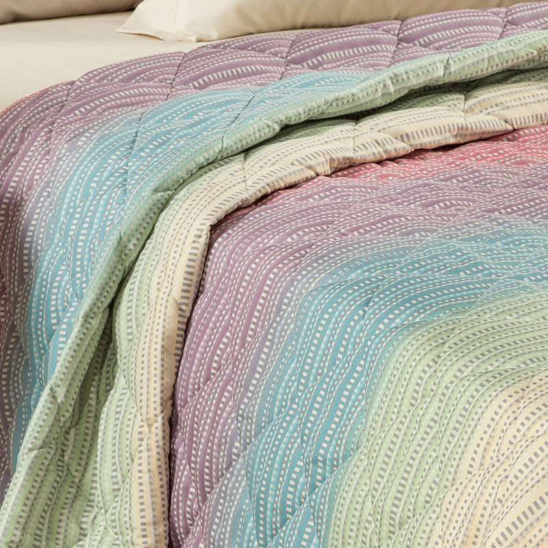 Trapuntino Caleffi Iride in morbida microfibra. Disponibile nella misura per letto singolo, piazza e mezza e matrimoniale. Trapunta primaverile dalla vivace fantasia geometrica con effetto degradè multicolor (arancio, verde,azzurro,rosa)