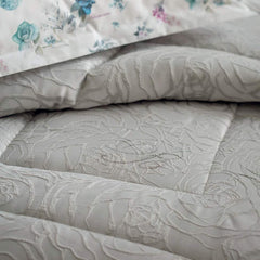 Trapunta invernale matrimoniale Dalida di Blumarine, in elegante raso jacquard. Il piumone Dalida presenta un'elegante fantasia floreale tinta in filo, con logo Blumarine in cristalli. Colore seppia beige. dettaglio fantasia