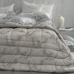 Trapunta Invernale matrimoniale Gemma di Blumarine, in elegante raso jacquard.Fantasia tinta in filo dalle forme morbide, nella variante di colore tortora, con logo Blumarine in preziosi cristalli Swarovski.