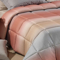 Trapunta invernale Caleffi Larry. Piumone con fantasia geometrica degradè grigio e corallo.