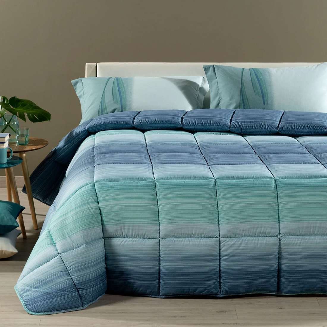 Trapunta invernale Caleffi Rainbow in microfibra. Disponibile nella misura per letto singolo. Fantasia moderna a righe con effetto degradè colore blu verde acqua