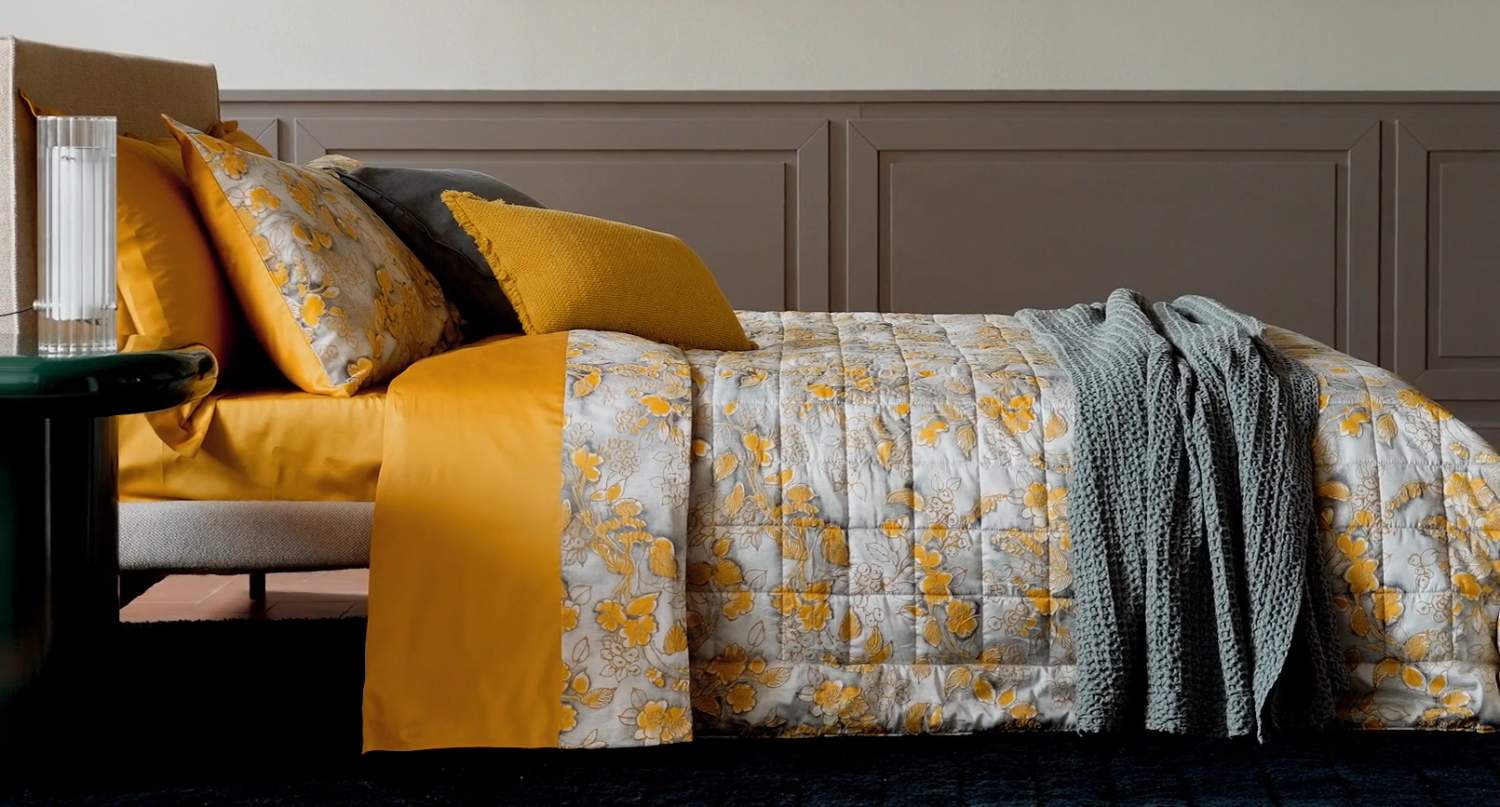 Trapunta primaverile matrimoniale Fazzini Chinoiserie, in raso di puro cotone. La passione per le ceramiche orientali anima la collezione Chinoiserie. Il disegno floreale variente oro ocra emerge sul fondo dall'effetto acquerellato e diventa tridimensionale grazie al profilo floccato e dorato. Il trapuntino Chinoiserie ha una fantasia floreale dorata su fondo verde acqua. Il quilt Chinoiserie è trapuntato a capo e rifinito a mano con due angoli sagomati.