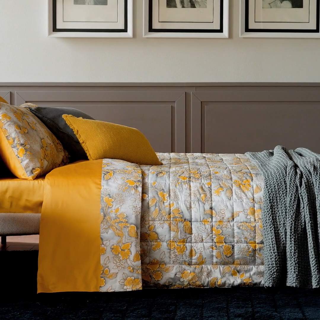Trapunta primaverile matrimoniale Fazzini Chinoiserie, in raso di puro cotone. La passione per le ceramiche orientali anima la collezione Chinoiserie. Il disegno floreale variente oro ocra emerge sul fondo dall'effetto acquerellato e diventa tridimensionale grazie al profilo floccato e dorato. Il trapuntino Chinoiserie ha una fantasia floreale dorata su fondo verde acqua. Il quilt Chinoiserie è trapuntato a capo e rifinito a mano con due angoli sagomati.