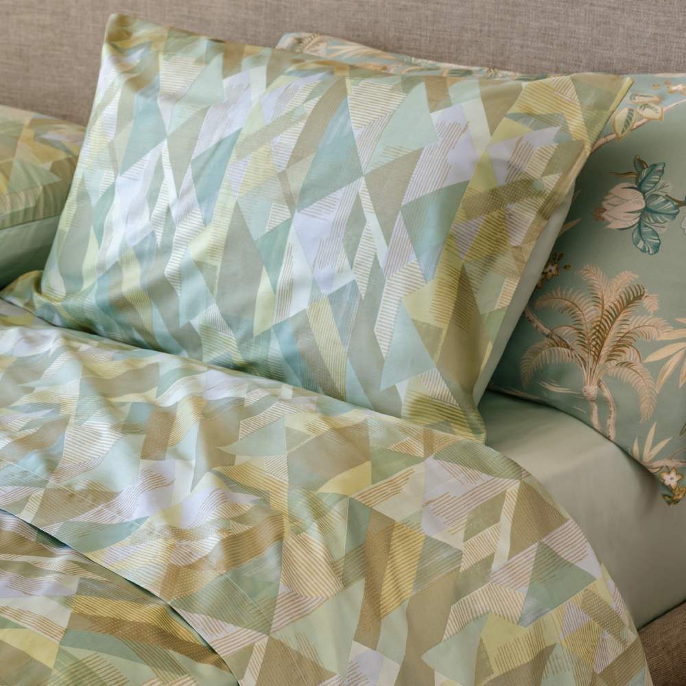 Trapunta primaverile matrimoniale Fazzini Symphonic, in percalle di puro cotone. Il trapuntino Symphonic presenta una moderna fantasia geometrica nel colore verde acqua (gray green). Il quilt è trapuntato a capo e rifinito a mano con due angoli sagomati che lo adattano perfettamente agli angoli del letto