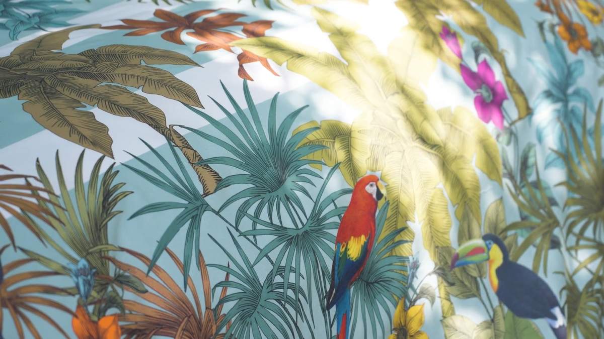 Trapunta primaverile matrimoniale Fazzini Kerala, in percalle di puro cotone. La collezione Kerala rappresenta un viaggio nella natura lussureggiante e incontaminata dell'India. Nel disegno la vegetazione tropicale, abitata da pappagalli dal piumaggio variopinto, si intreccia con un motivo rigato degradè colore verde acqua (variante surf). Il quilt è trapuntato a capo e rifinito a mano con due angoli sagomati che lo adattano perfettamente agli angoli del letto.