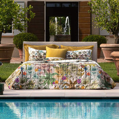 Trapunta primaverile matrimoniale Fazzini Kerala, in percalle di puro cotone. La collezione Kerala rappresenta un viaggio nella natura lussureggiante e incontaminata dell'India. Nel disegno la vegetazione tropicale, abitata da pappagalli dal piumaggio variopinto, si intreccia con un motivo rigato degradè colore verde acqua (variante surf). Il quilt è trapuntato a capo e rifinito a mano con due angoli sagomati che lo adattano perfettamente agli angoli del letto.