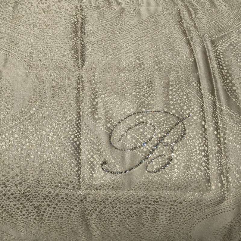 Trapuntino matrimoniale Crystelle di Blumarine, in elegante raso jacquard. Sinuosa fantasia jacquard dalle forme morbide, con inserti in lurex e logo Blumarine in cristalli. Disponibile nella variante di colore cera tortora