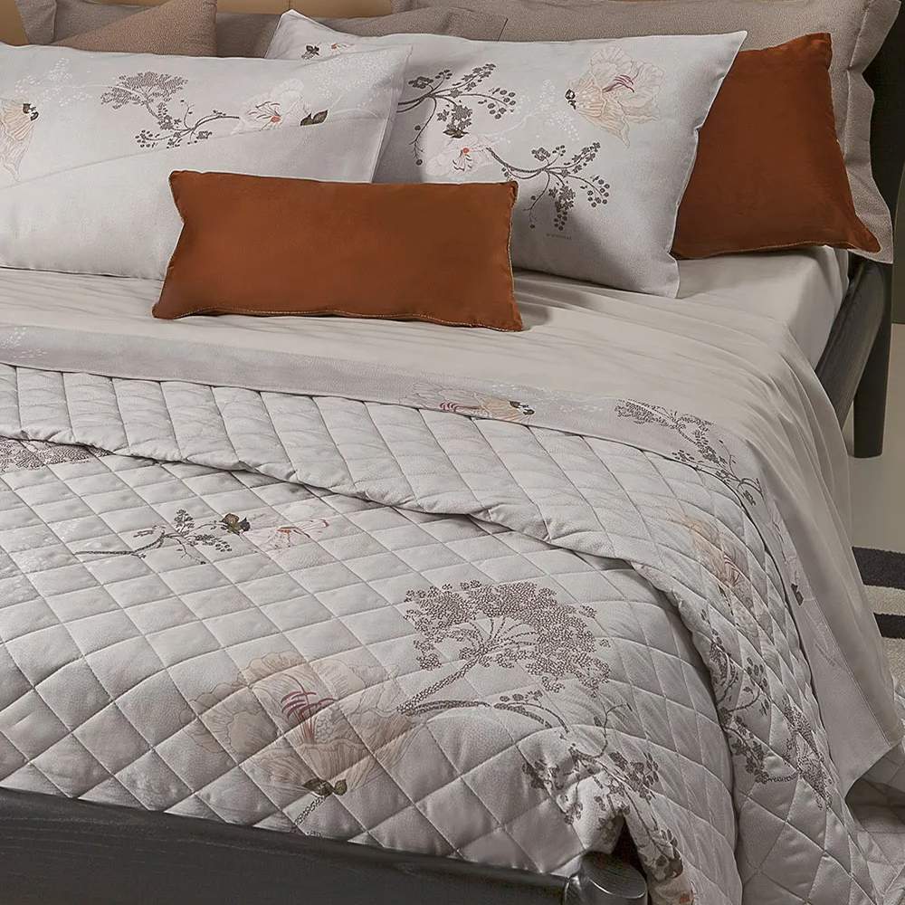 Trapuntino matrimoniale Crystal Borbonese, in raso di puro cotone stampato. Variante pesca. La trapunta primaverile Crystal è caratterizzata da una fantasia floreale dai toni delicati, con fiori color pesca e fondo beige con la tipica stampa Borbonese a occhio di pernice. Trapunta rifinita a mano con angoli stondati.