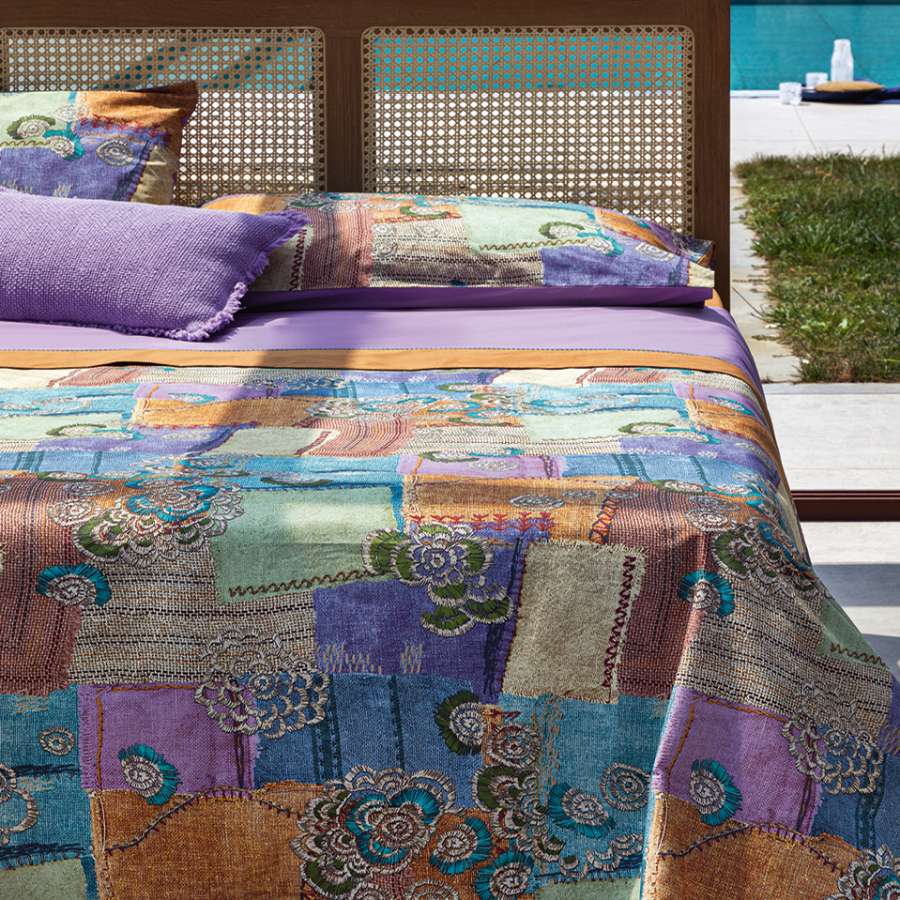 Trapunta primaverile matrimoniale Fazzini Crazy Quilt, in percalle di puro cotone. La collezione Crazy Quilt, col il suo spirito vagamente bohémienne, restituisce attraverso la stampa l'idea del patchwork, ma anche la matericità del lino e del rammendo che diventa ricamo. La trapuntatura del quilt valorizza l'effetto tridimensionale della fantasia. Il quilt è trapuntato a capo e rifinito a mano con due angoli sagomati che lo adattano perfettamente agli angoli del letto.