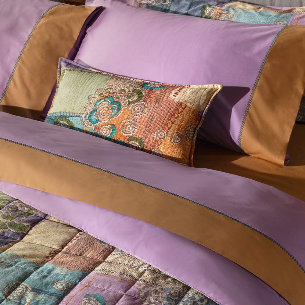 Trapunta primaverile matrimoniale Fazzini Crazy Quilt, in percalle di puro cotone. La collezione Crazy Quilt, col il suo spirito vagamente bohémienne, restituisce attraverso la stampa l'idea del patchwork, ma anche la matericità del lino e del rammendo che diventa ricamo. La trapuntatura del quilt valorizza l'effetto tridimensionale della fantasia. Il quilt è trapuntato a capo e rifinito a mano con due angoli sagomati che lo adattano perfettamente agli angoli del letto.