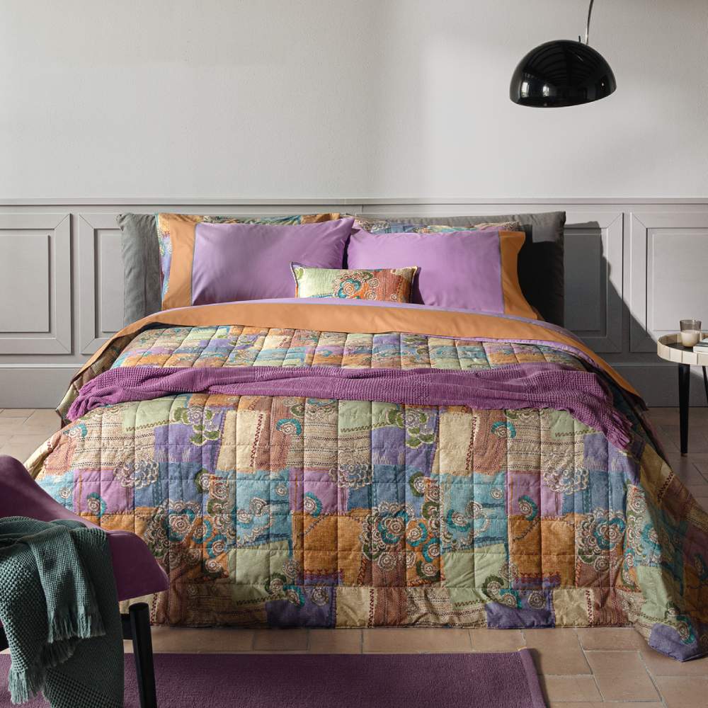 Trapunta primaverile matrimoniale Fazzini Crazy Quilt, in percalle di puro cotone. La collezione Crazy Quilt, col il suo spirito vagamente bohémienne, restituisce attraverso la stampa l'idea del patchwork, ma anche la matericità del lino e del rammendo che diventa ricamo. La trapuntatura del quilt valorizza l'effetto tridimensionale della fantasia. Il quilt è trapuntato a capo e rifinito a mano con due angoli sagomati che lo adattano perfettamente agli angoli del letto.