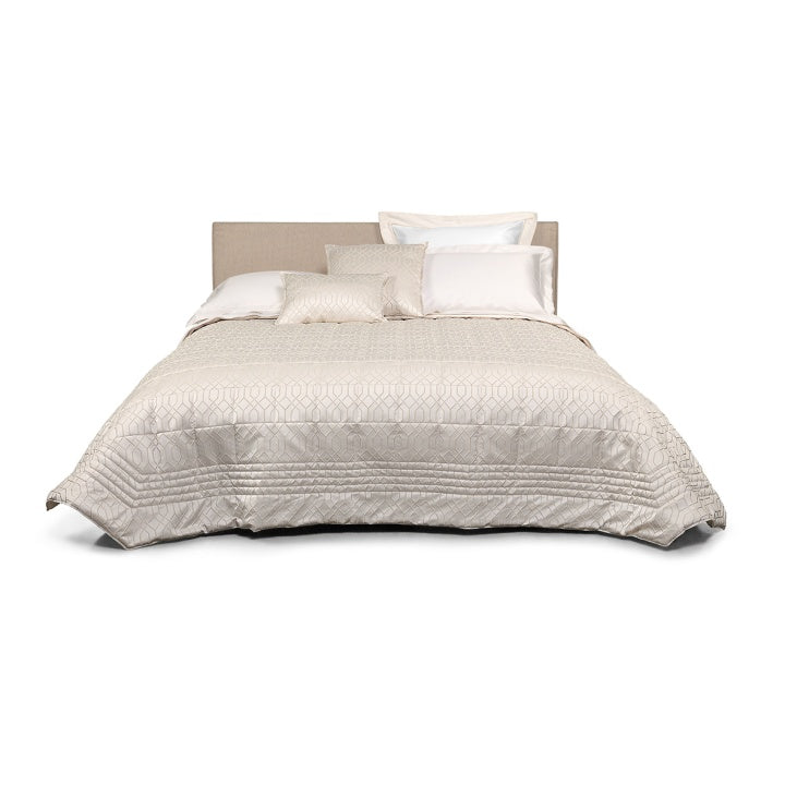 Trapuntino matrimoniale Villa Necchi, della linea Fazzini Atelier, in prezioso raso jacquard. Il quilt Villa Necchi presenta in un gioco tono su tono un bel motivo tridimensionale d'ispirazione dèco, con una mano morbida e voluminosa. Variante di colore champagne/avorio. La trapunta primaverile Villa Necchi è trapuntata a capo e rifinita a mano con due angoli sagomati che la adattano perfettamente agli angoli del letto