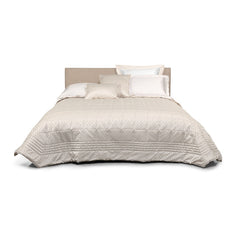 Trapuntino matrimoniale Villa Necchi, della linea Fazzini Atelier, in prezioso raso jacquard. Il quilt Villa Necchi presenta in un gioco tono su tono un bel motivo tridimensionale d'ispirazione dèco, con una mano morbida e voluminosa. Variante di colore champagne/avorio. La trapunta primaverile Villa Necchi è trapuntata a capo e rifinita a mano con due angoli sagomati che la adattano perfettamente agli angoli del letto