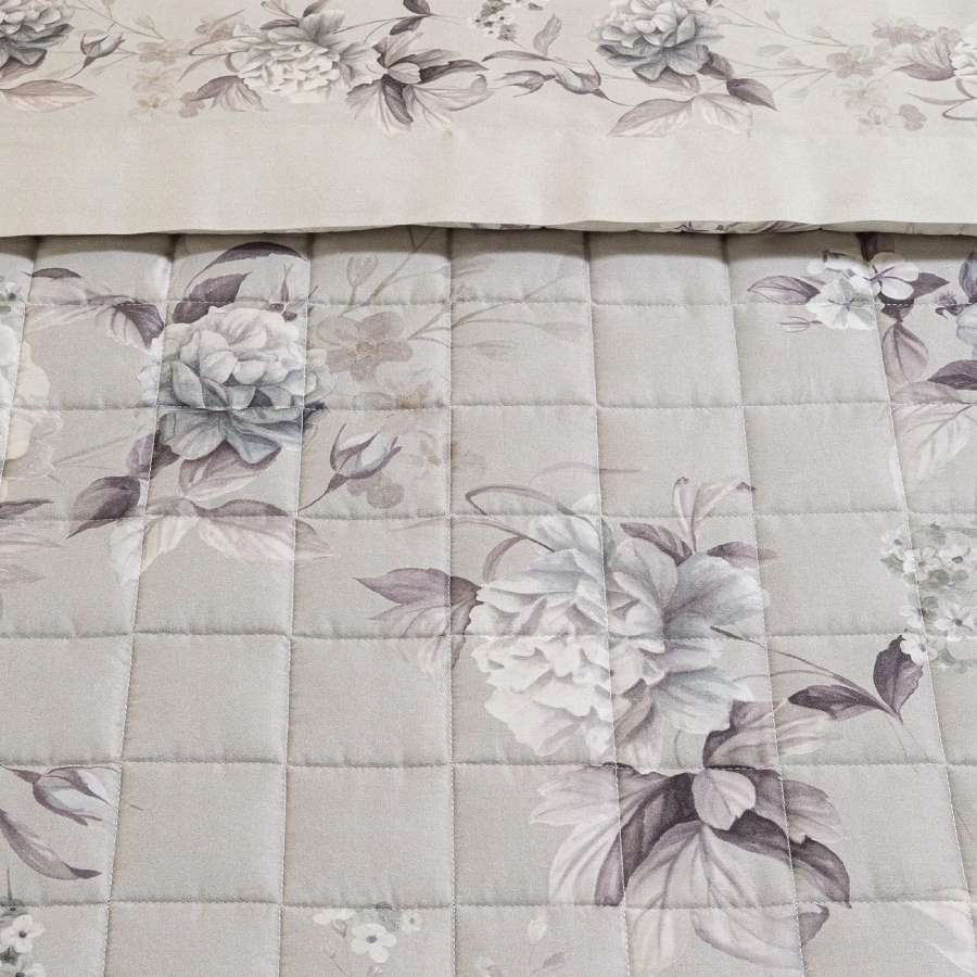 Trapuntino matrimoniale Caleffi Fior di Luna, in raso di puro cotone con stampa digitale di alta qualità. La trapunta primaverile Fior di Luna presenta una delicata fantasia floreale con fiori chiari su fondo grigio. Dettaglio fantasia.