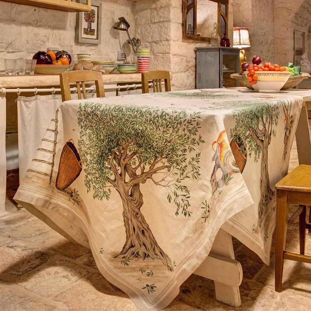 Tovaglia D.O.P. in puro lino stampato con disegno piazzato. Realizzata in Italia da Tessitura Toscana Telerie.Una fantasia unica che racconta il legame con l'ulivo e l'amore per la terra. Fantasia con alberi d'ulivo su fondo beige.